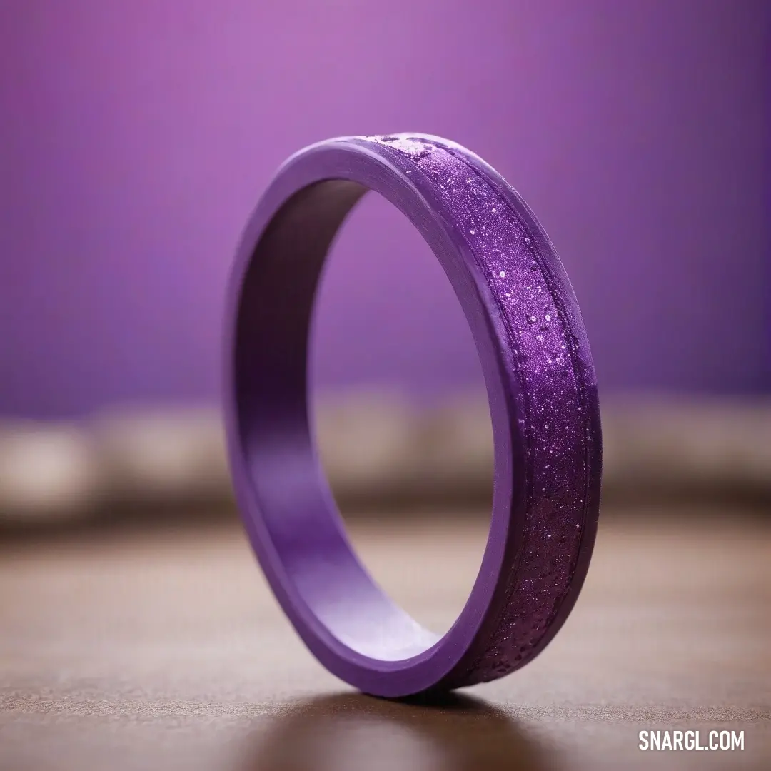 A purple ring with a glittery finish on its side, sitting on a dark table. The subtle interplay of light on the glittering surface creates a mesmerizing effect, enhanced by the surrounding dark brown tones.