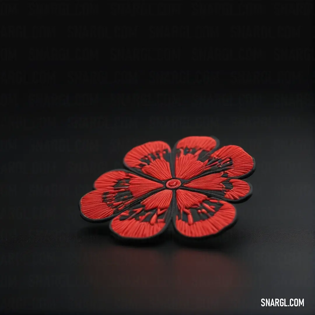 Red flower brooch on top of a black surface. Example of Dark coral color.