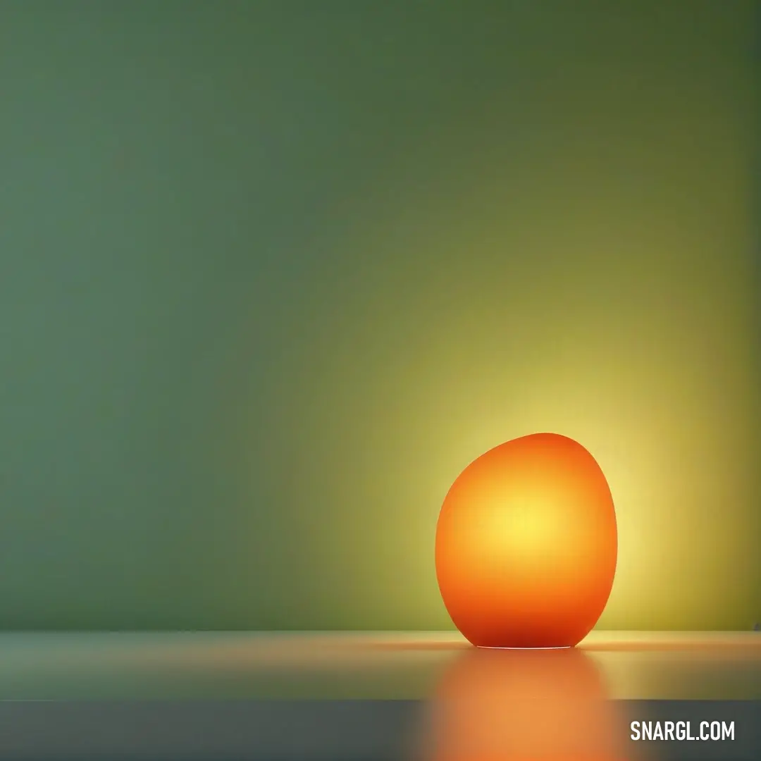 An orange ball rests on a table in front of a green wall, with light reflecting off the floor. The vibrant contrast between the warm orange and the cool green creates a lively and dynamic visual.