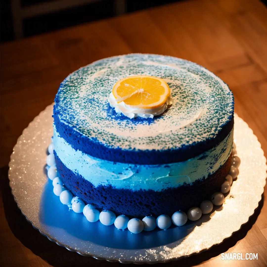 Blue and white cake with a slice of orange on top of it on a table