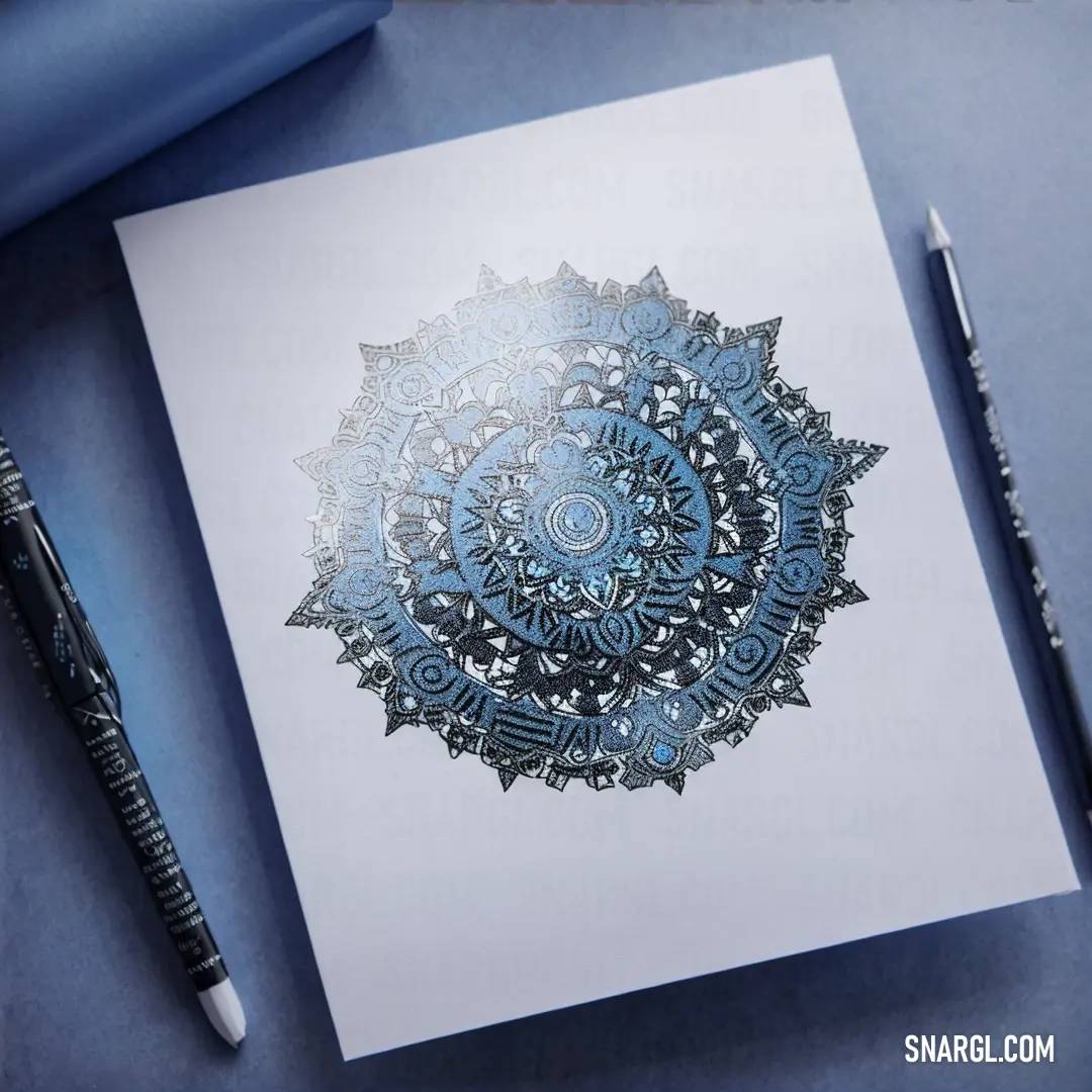 Drawing of a circular design on a white paper with a pen next to it on a blue surface