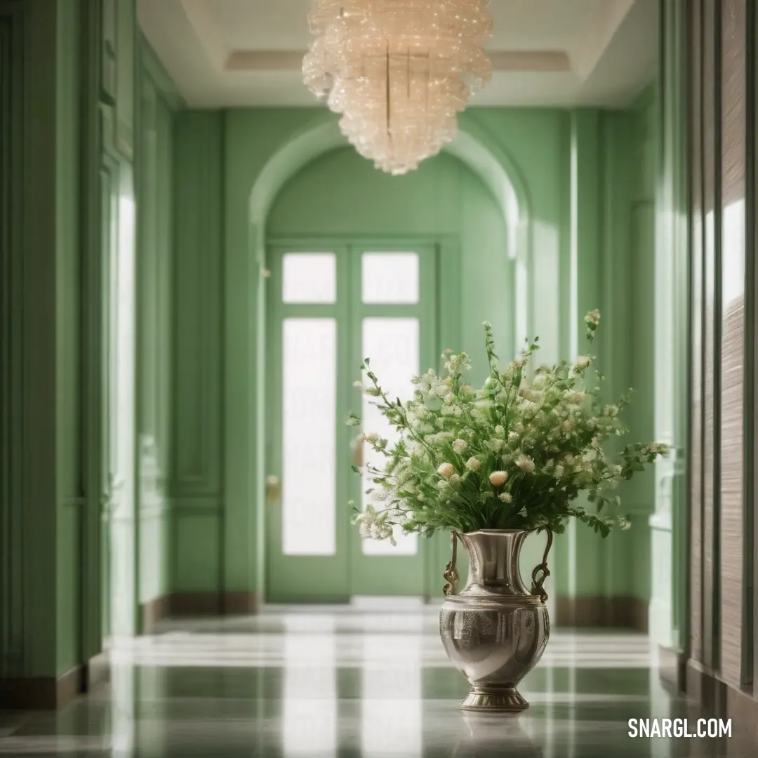 Vase with flowers in it on a table in a hallway with green walls and a chandelier. Color RGB 143,188,143.