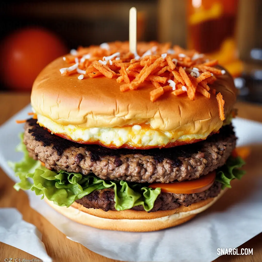 Hamburger with a candle on top of it on a plate with a napkin on it and a glass of juice in the background