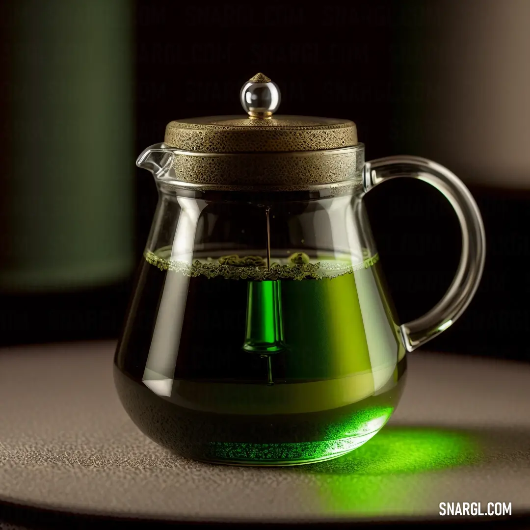 Glass tea pot with a green tea inside of it on a table top with a light shining on it