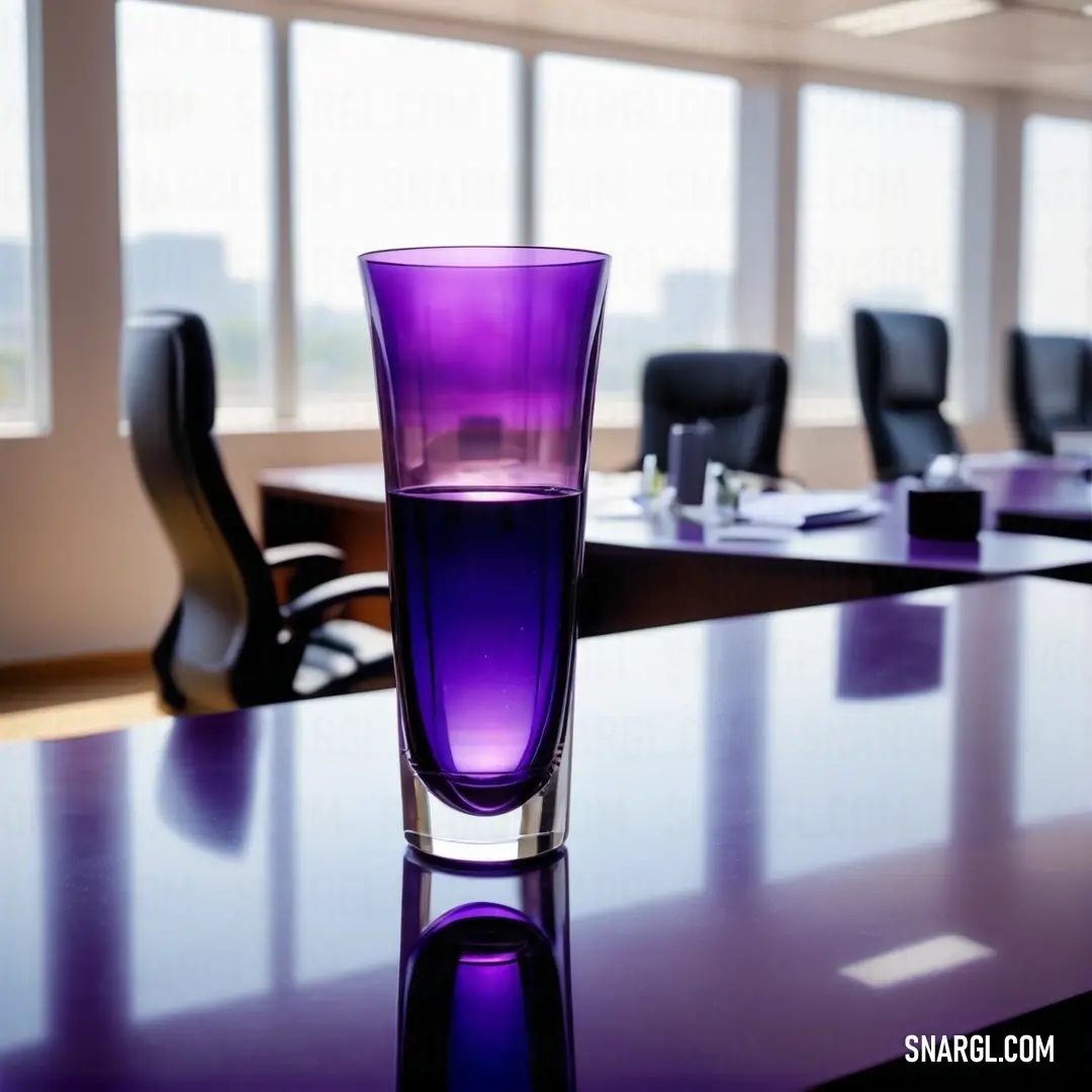 Purple glass on top of a table in a room with chairs and windows in the background. Example of Dark violet color.