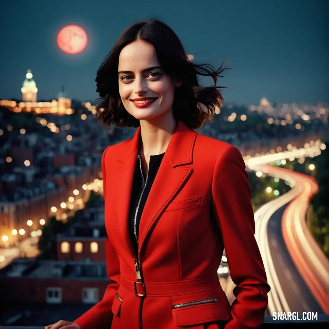 Woman in a red suit standing on a balcony at night with a city in the background. Color CMYK 0,80,77,6.