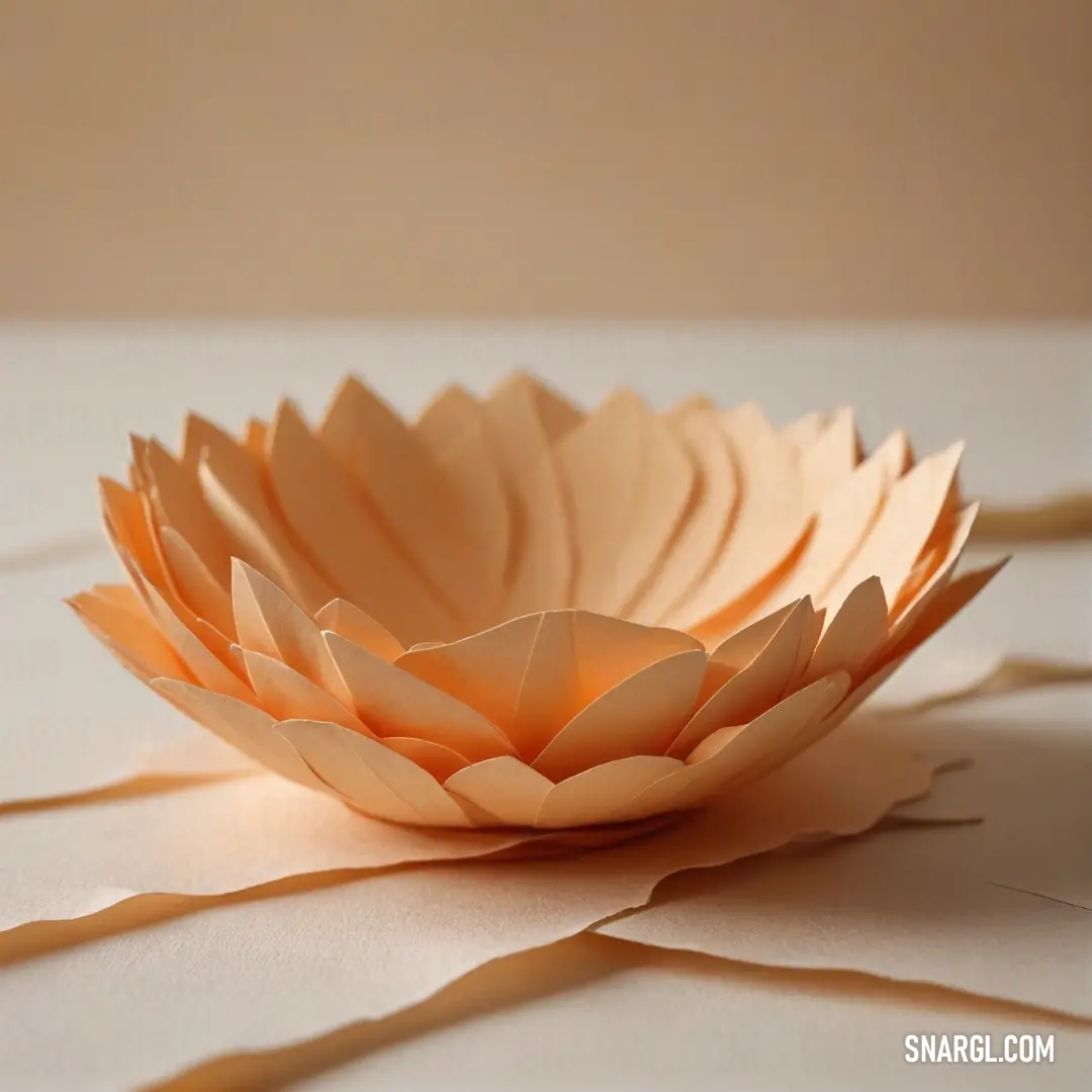 A delightful paper flower, showcasing a brilliant deep carrot orange hue, rests elegantly on a textured tabletop. A charming ribbon encircles its base, while a gentle sheet of paper lies nearby, creating a whimsical and artistic scene filled with creativi