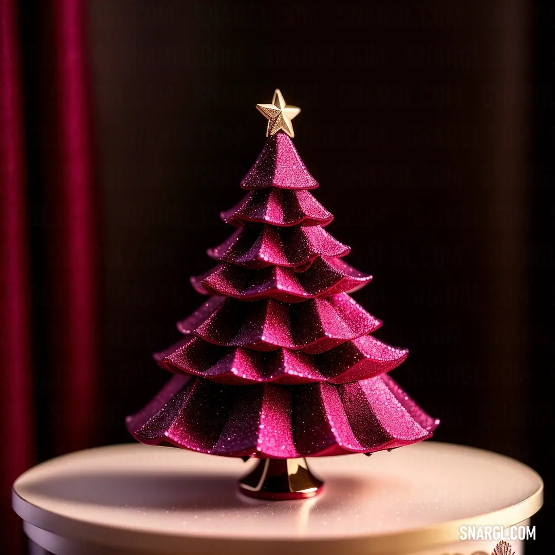 Pink christmas tree on a white table with a red curtain behind it and a gold star on top. Color #DA3287.