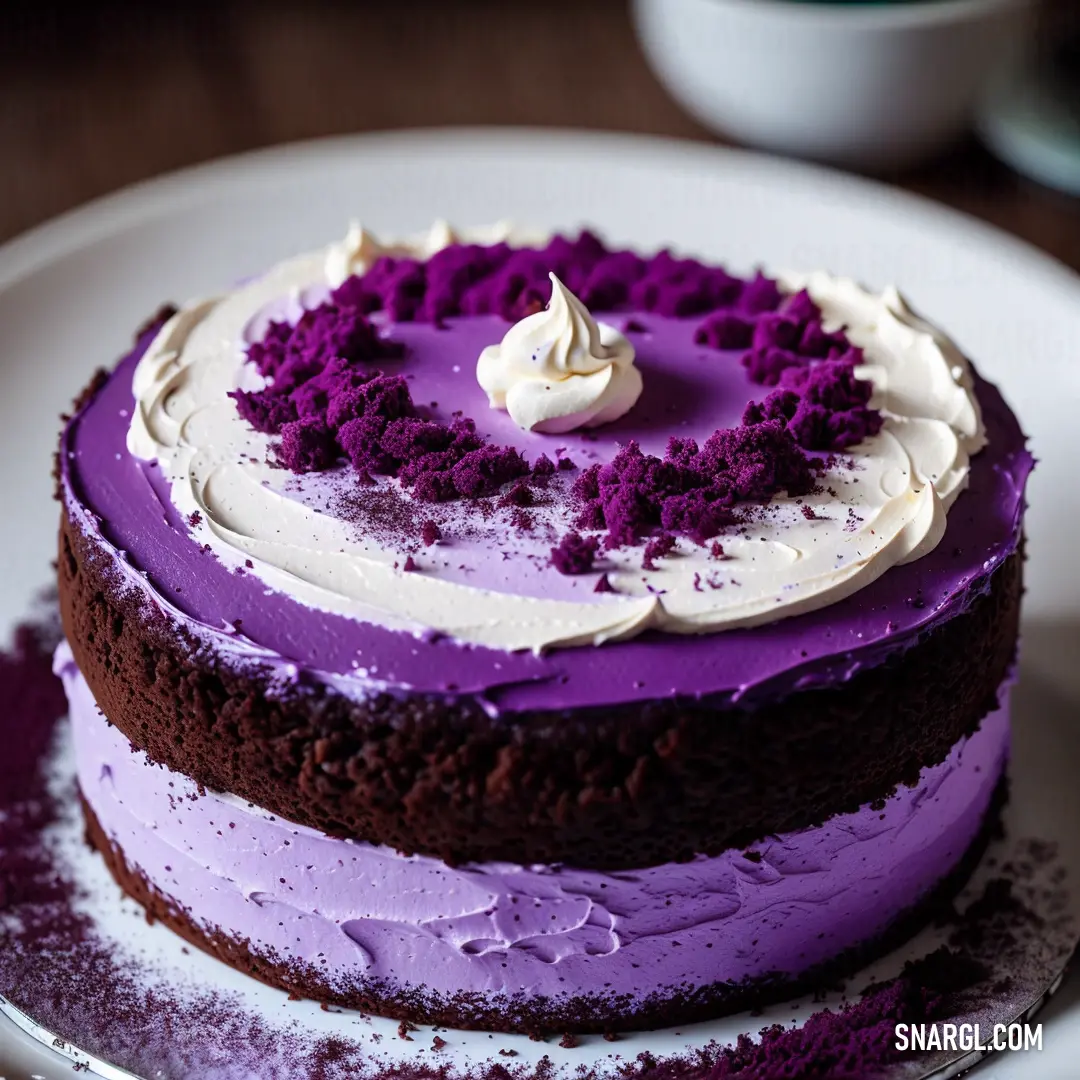 Cake with purple frosting on a white plate on a table with a cup of coffee in the background. Color #9955BB.