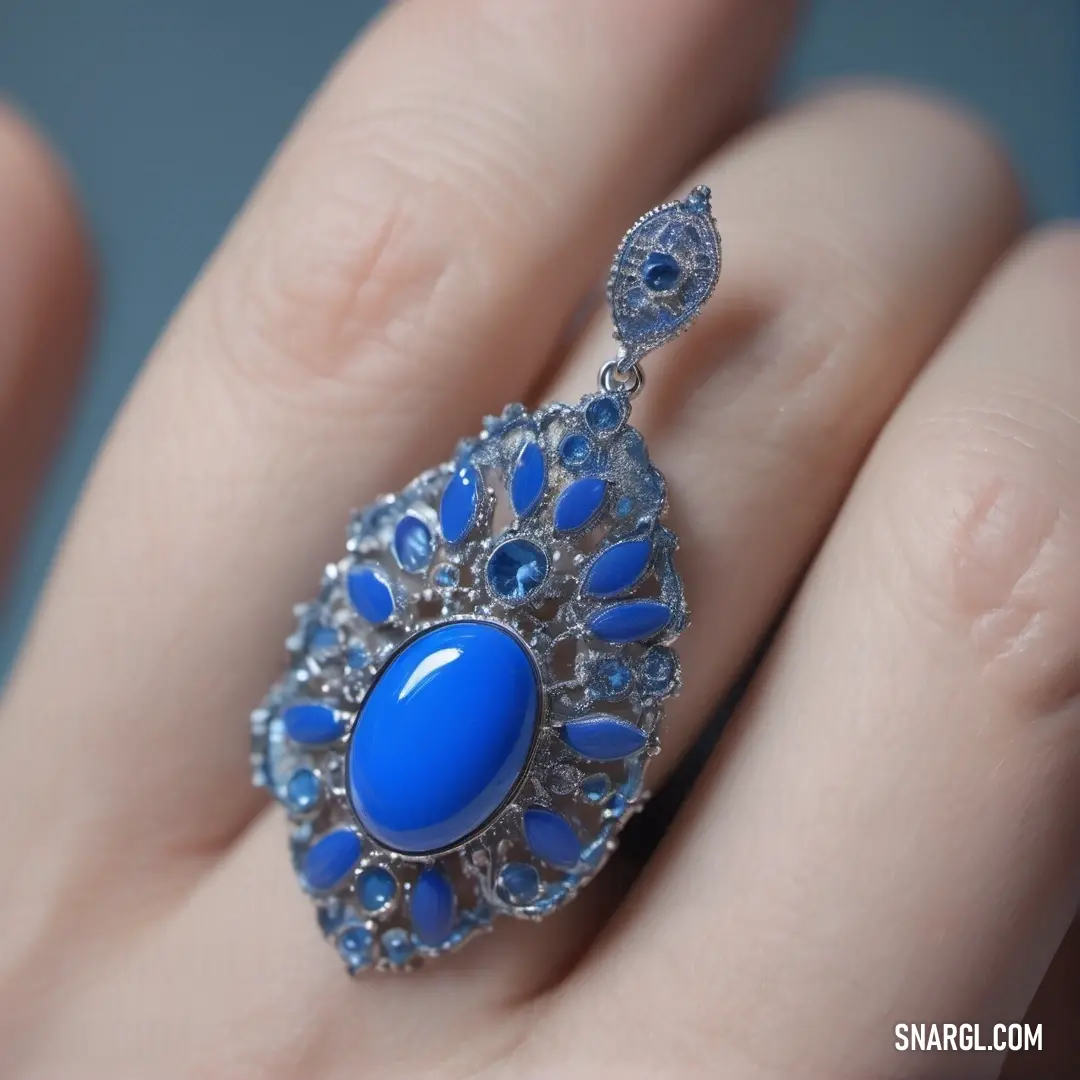 Denim color. Womans hand with a ring with a blue stone on it