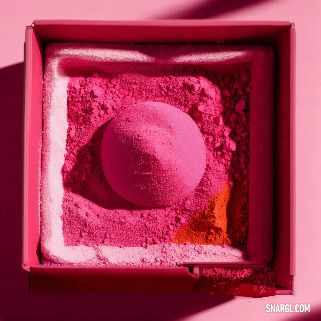 Pink powdered object in a pink box on a pink background with a shadow of a person's hand