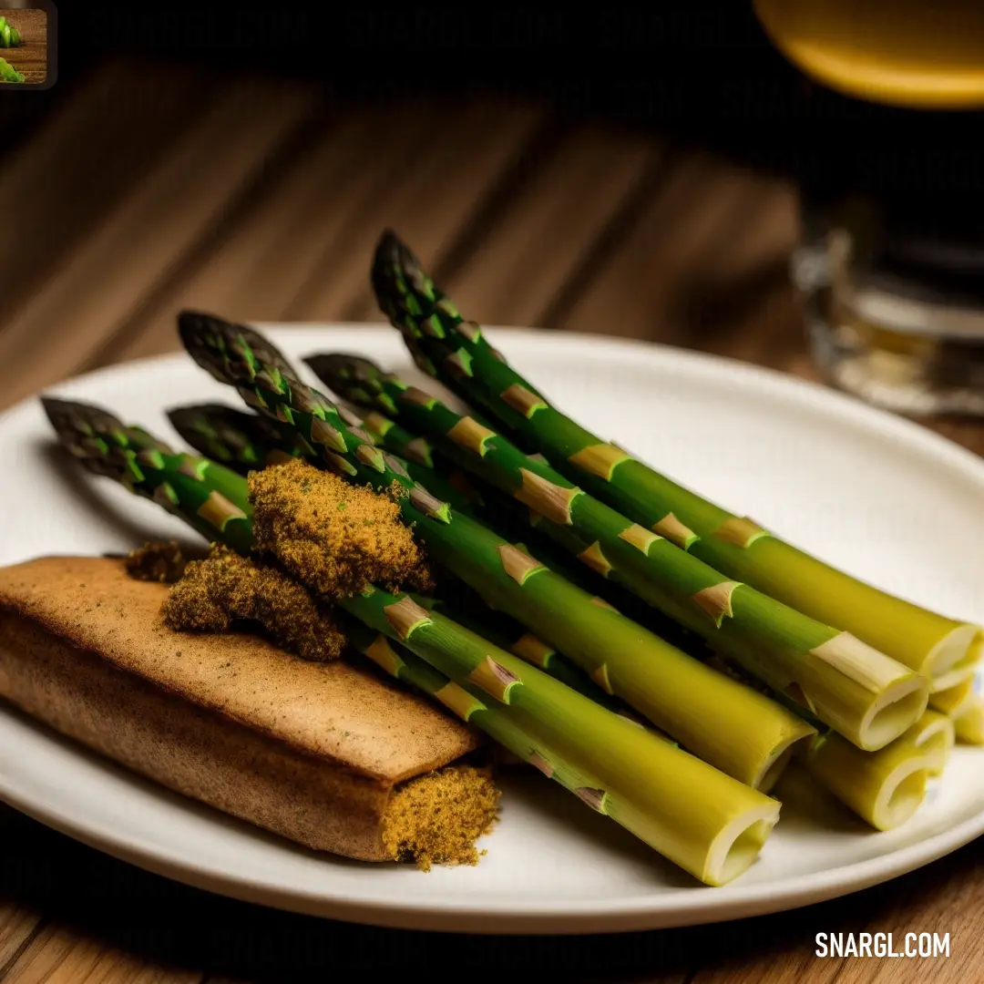 Plate with asparagus, bread and mustard on it and a glass of beer in the background. Example of CMYK 0,25,58,12 color.