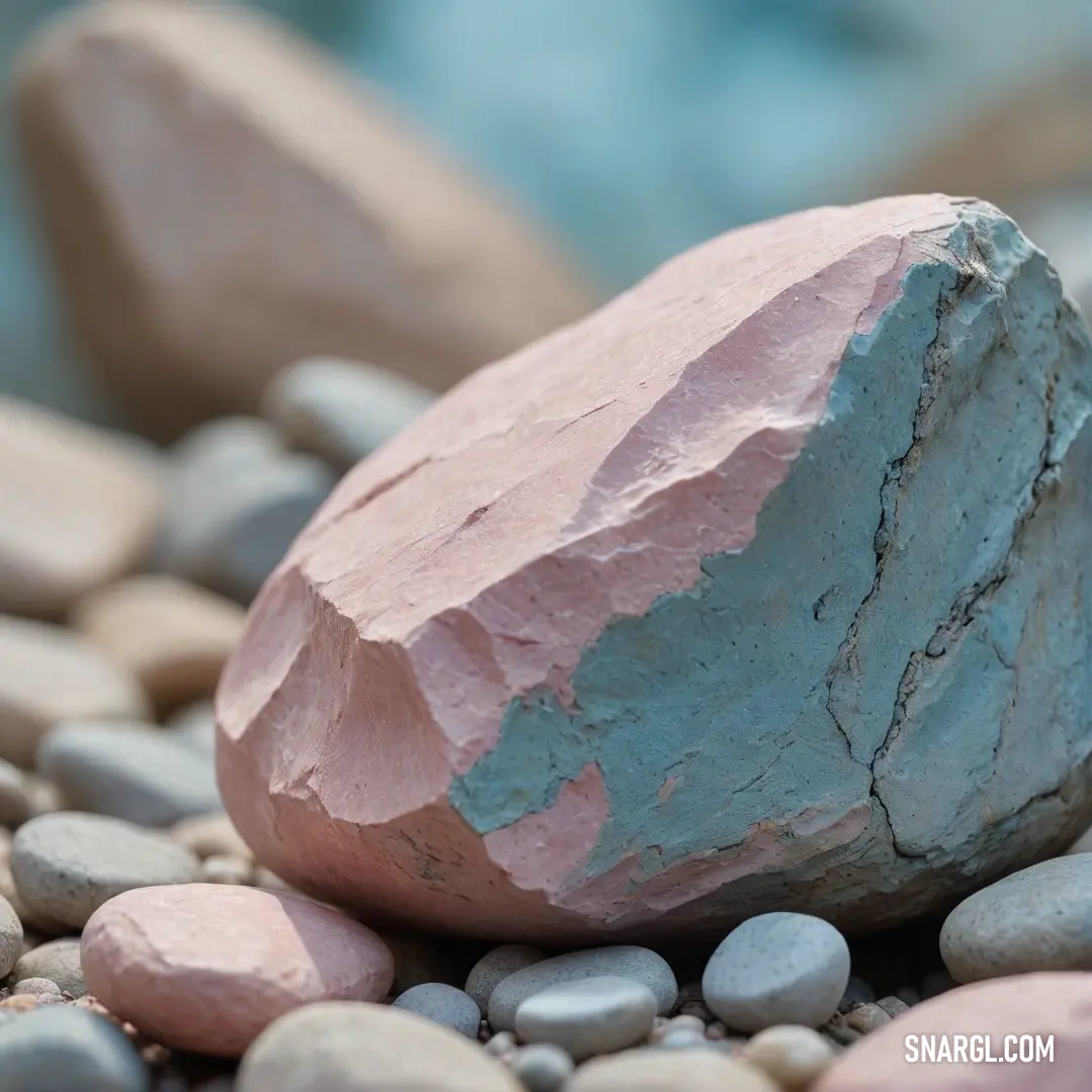 A striking rock majestically balanced atop a varied pile of stones, next to tranquil waters reflecting the natural world. The subtle color variations demonstrate the beauty of nature's artistry amid the earthy tones below and serene ripples above.