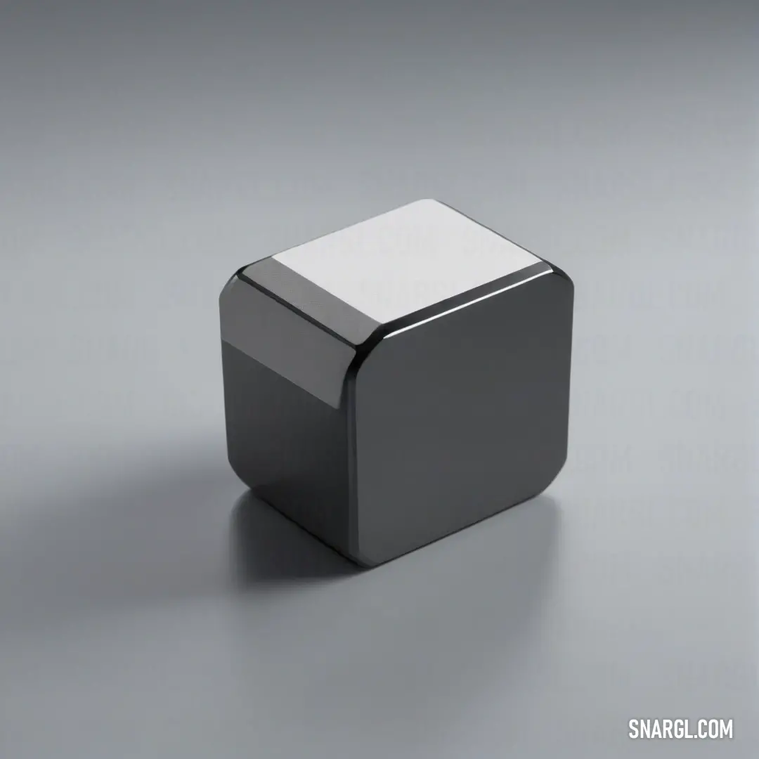 A small square object with a white top, sitting on a gray surface. A soft shadow stretches beneath it, emphasizing its clean, minimalistic design and the subtle interplay of light and geometry.