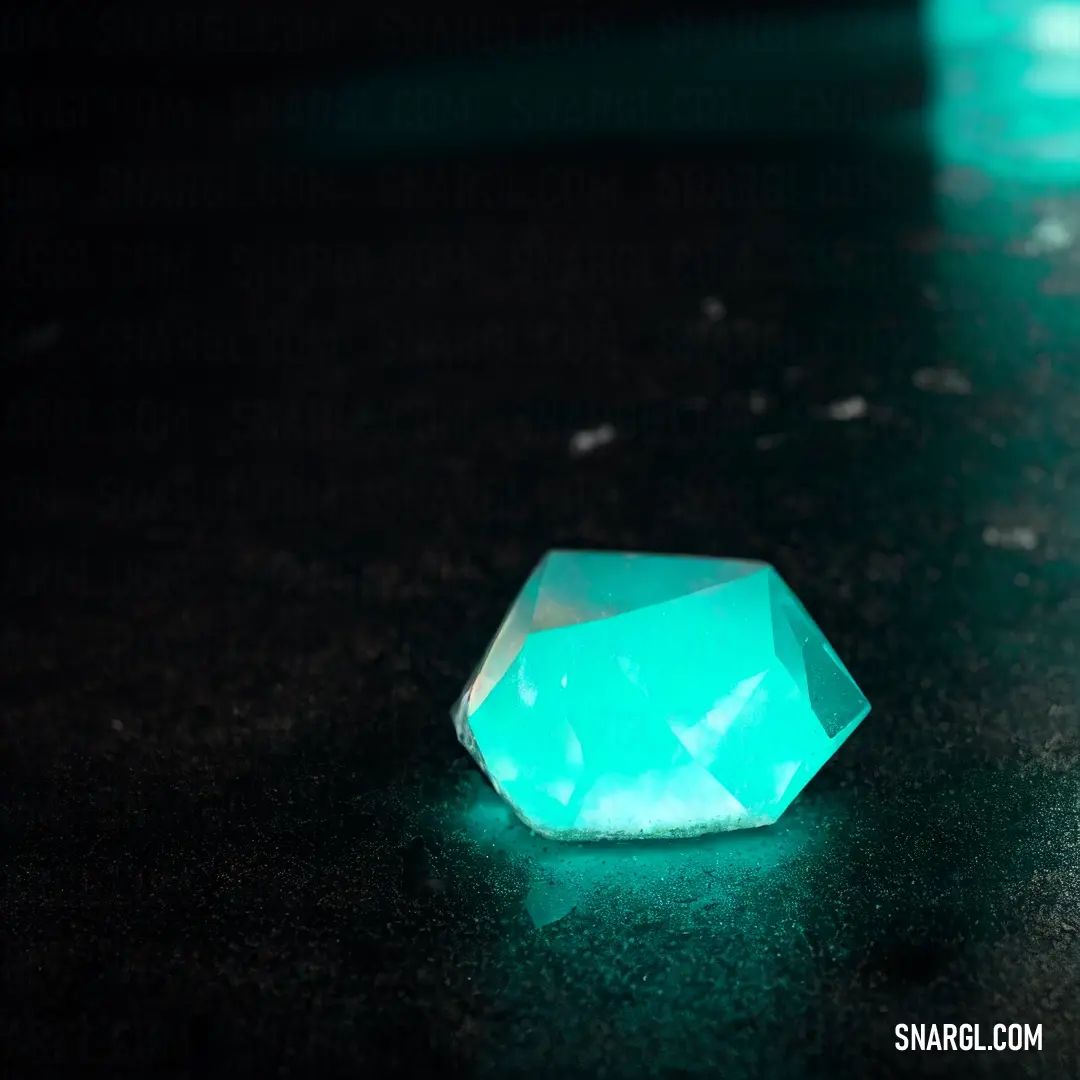 Green diamond on a black table top with a green light shining on it's side