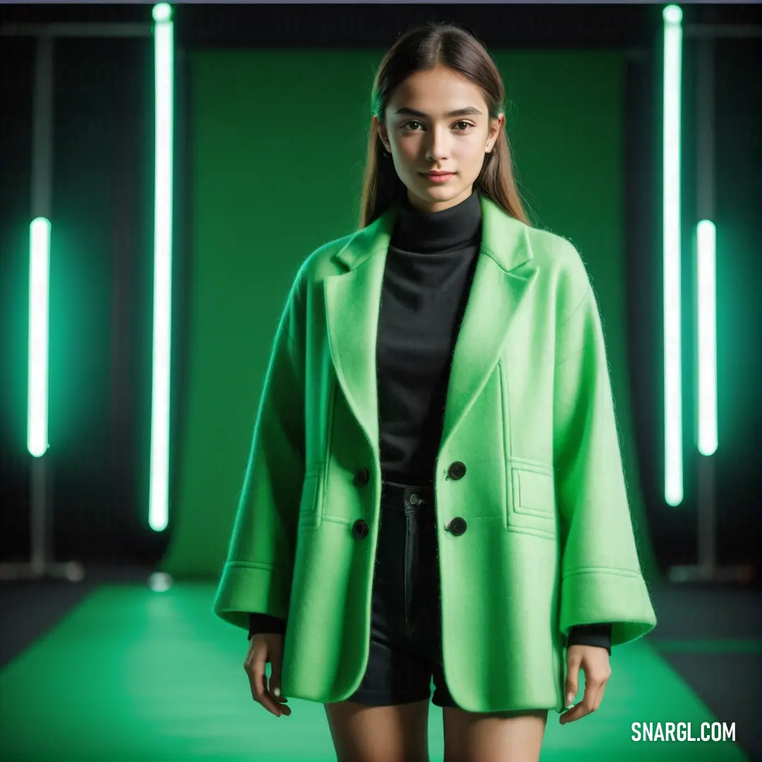 Woman in a green coat and black top on a green background with neon lights behind her and a green backdrop. Example of CMYK 60,0,40,22 color.