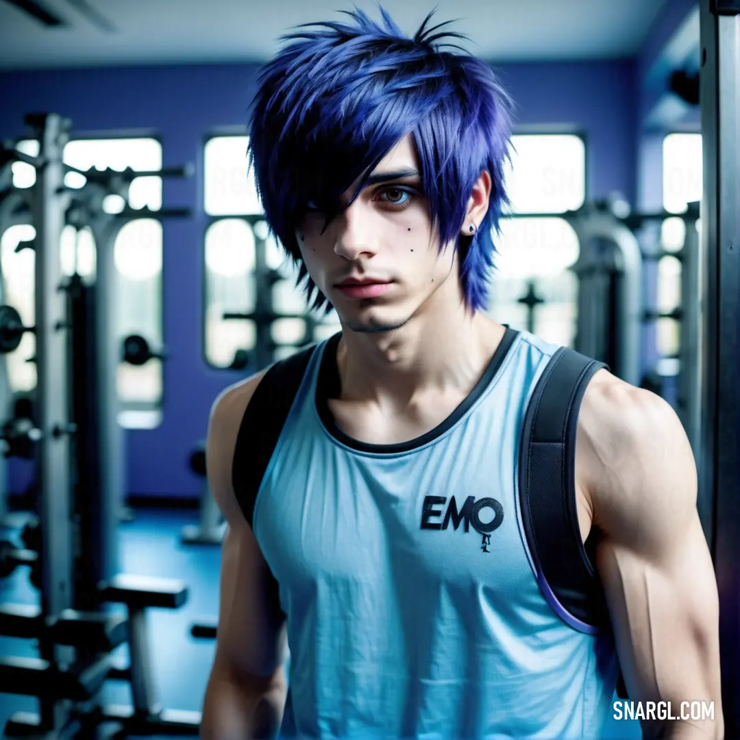 Man with blue hair standing in a gym with a rack of exercise equipment behind him and looking at the camera
