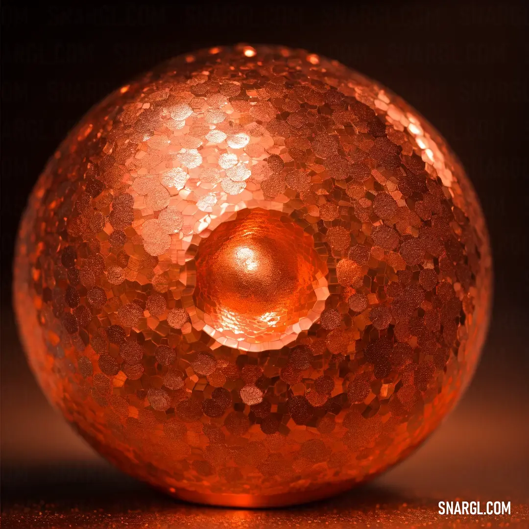Shiny orange ball with a hole in the middle of it on a table top with a black background