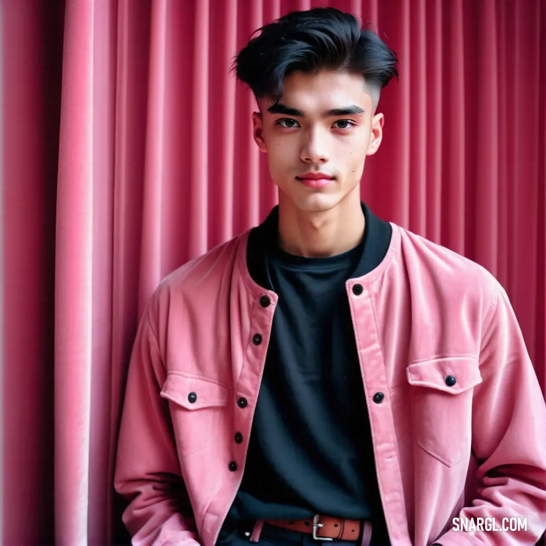 Man standing in front of a pink curtain wearing a black shirt and black pants. Example of CMYK 0,44,32,1 color.