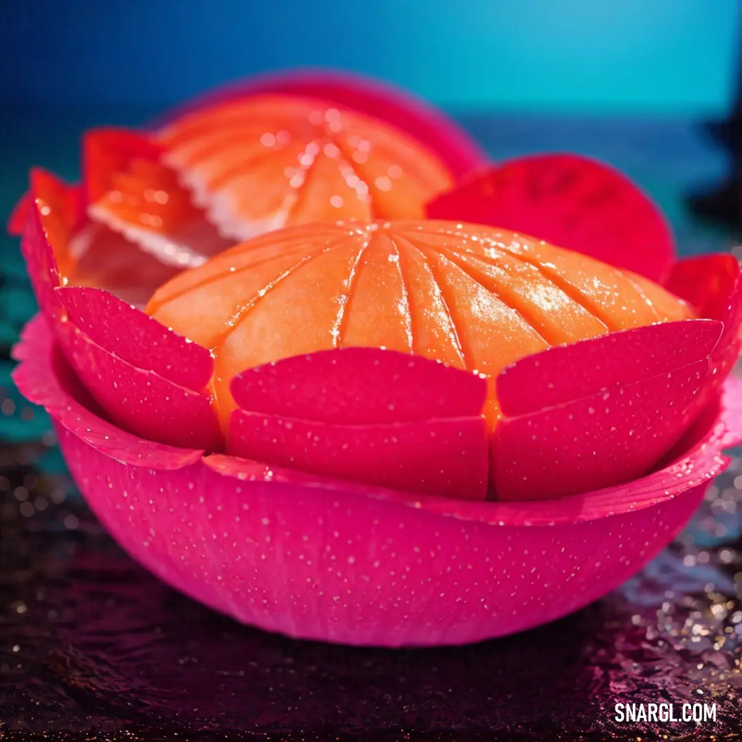 Pink bowl with oranges and water droplets on it and a blue background