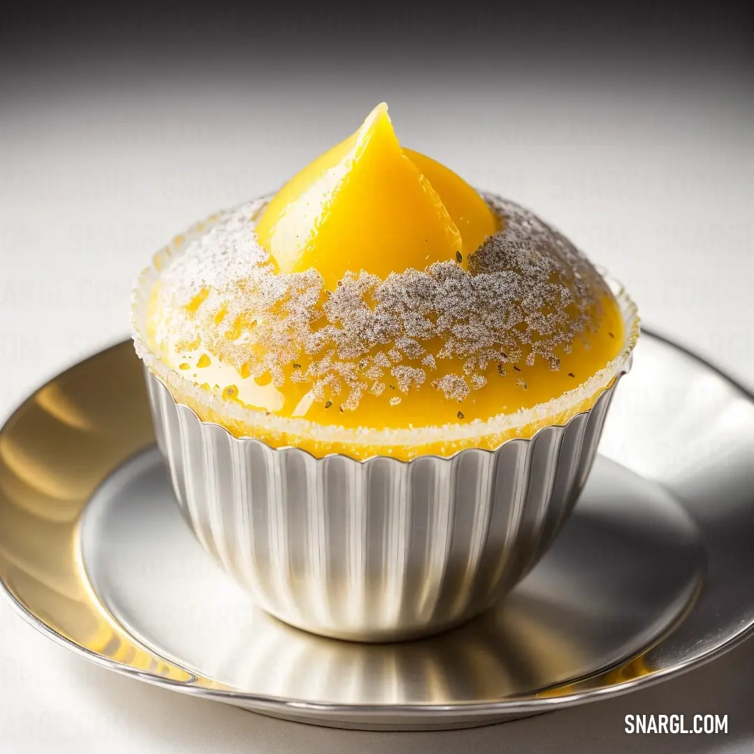 Cupcake with a lemon wedge on top of it on a plate with a silver rim