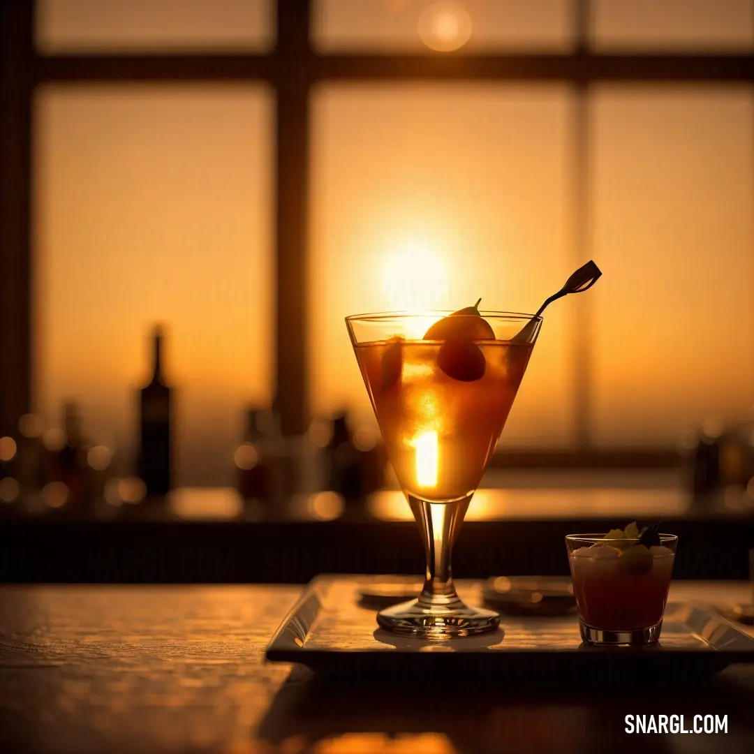 Drink in a glass with a spoon in it on a table with a window in the background and a tray with a drink on it