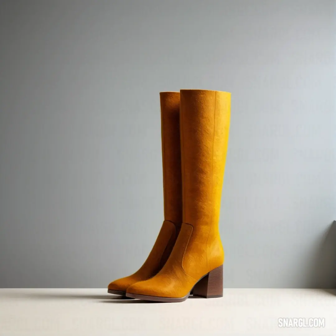 Pair of yellow boots on top of a table next to a wall and a window frame with a gray background. Color RGB 228,155,15.