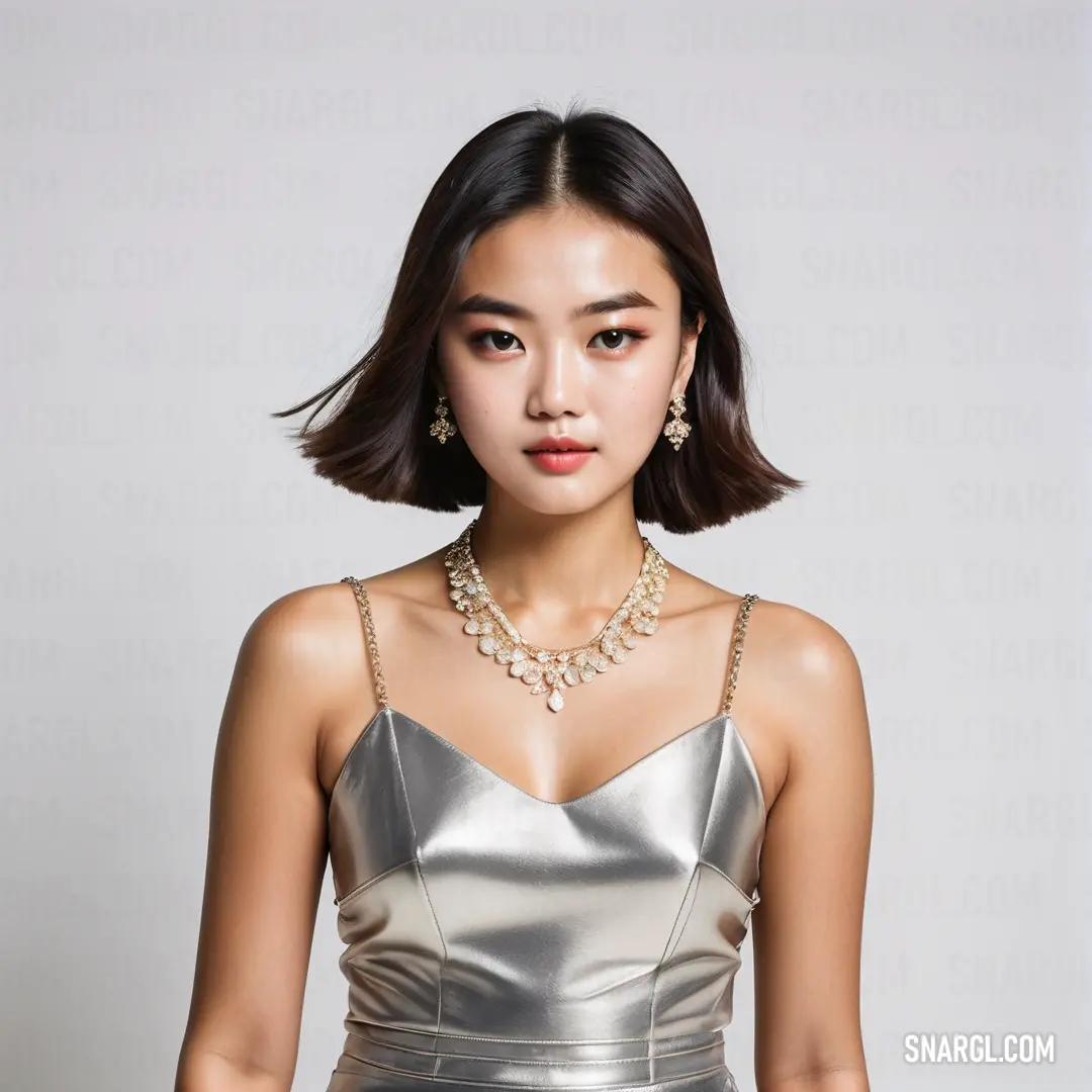 A woman stands in an elegant silver dress, with a delicate necklace around her neck. The soft glow from the ambient light highlights the shimmering fabric of her dress, and her confident yet graceful posture adds to the enchanting aura surrounding her.