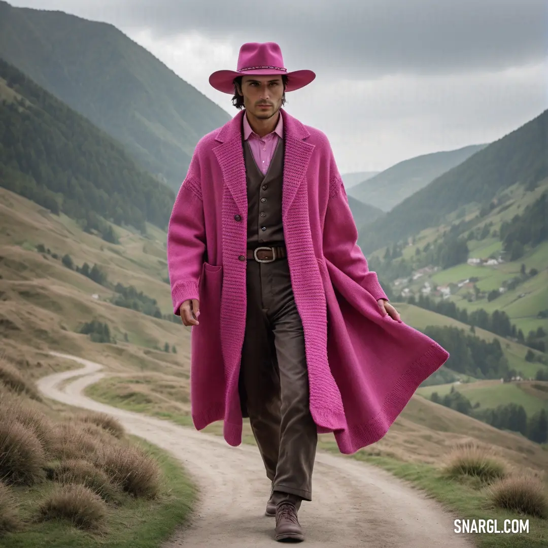 Man in a pink coat and hat walking down a dirt road in the mountains
