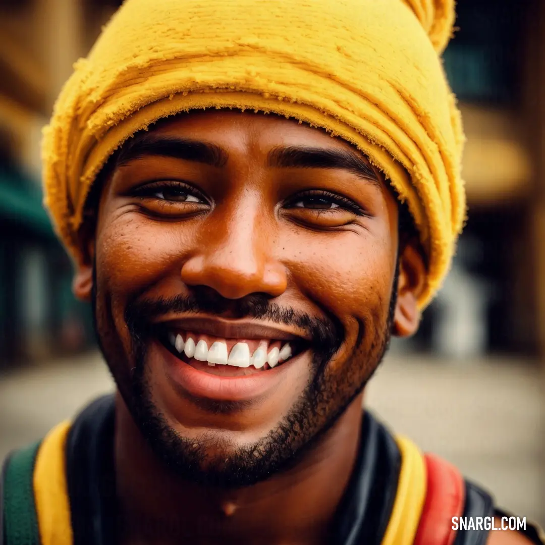 Man with a yellow turban smiles for the camera while wearing a yellow hat and a black vest