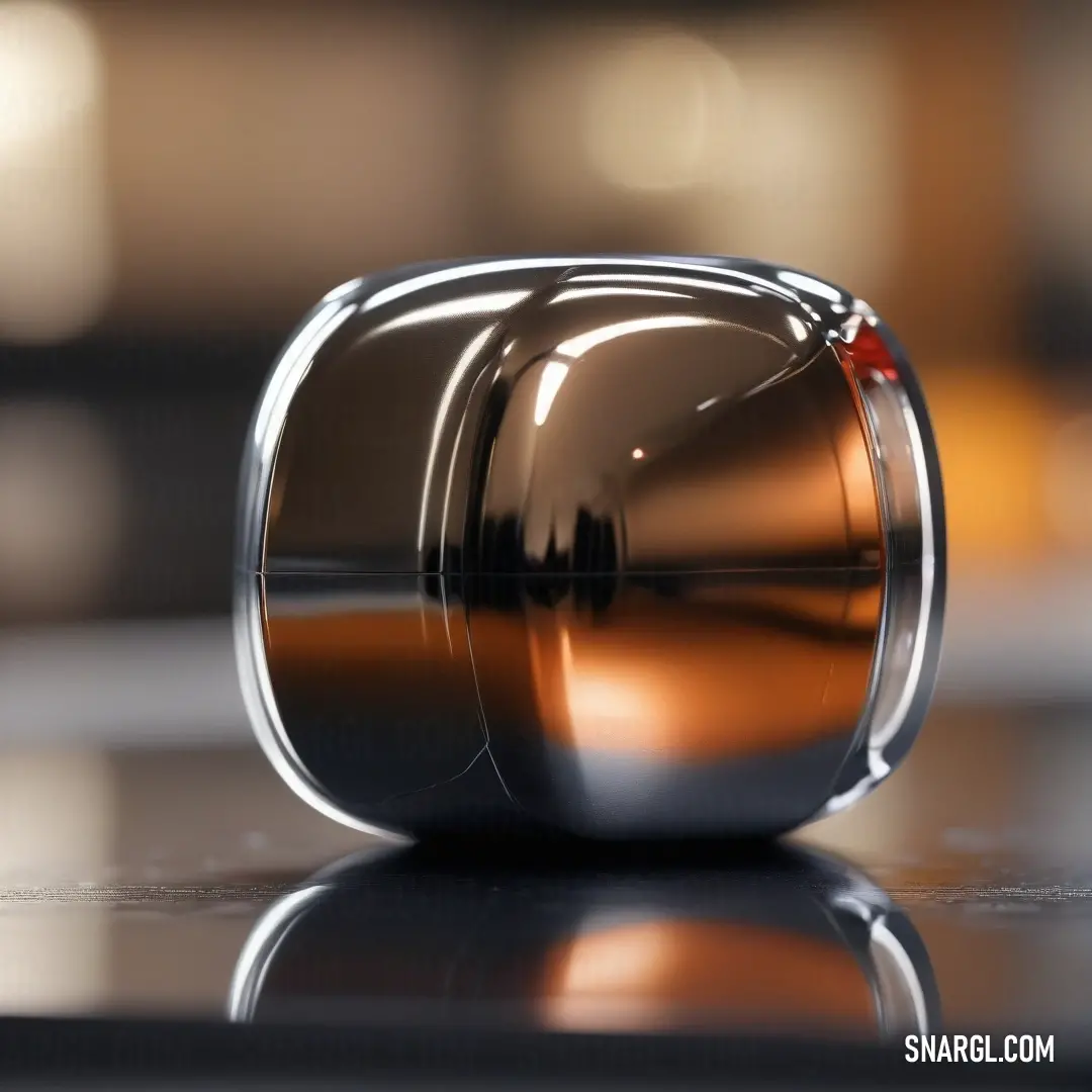 A shiny metal object resting on a smooth, reflective surface, with a soft-focus background. The warm hue of the metal catches the light, adding depth and intrigue to the scene.