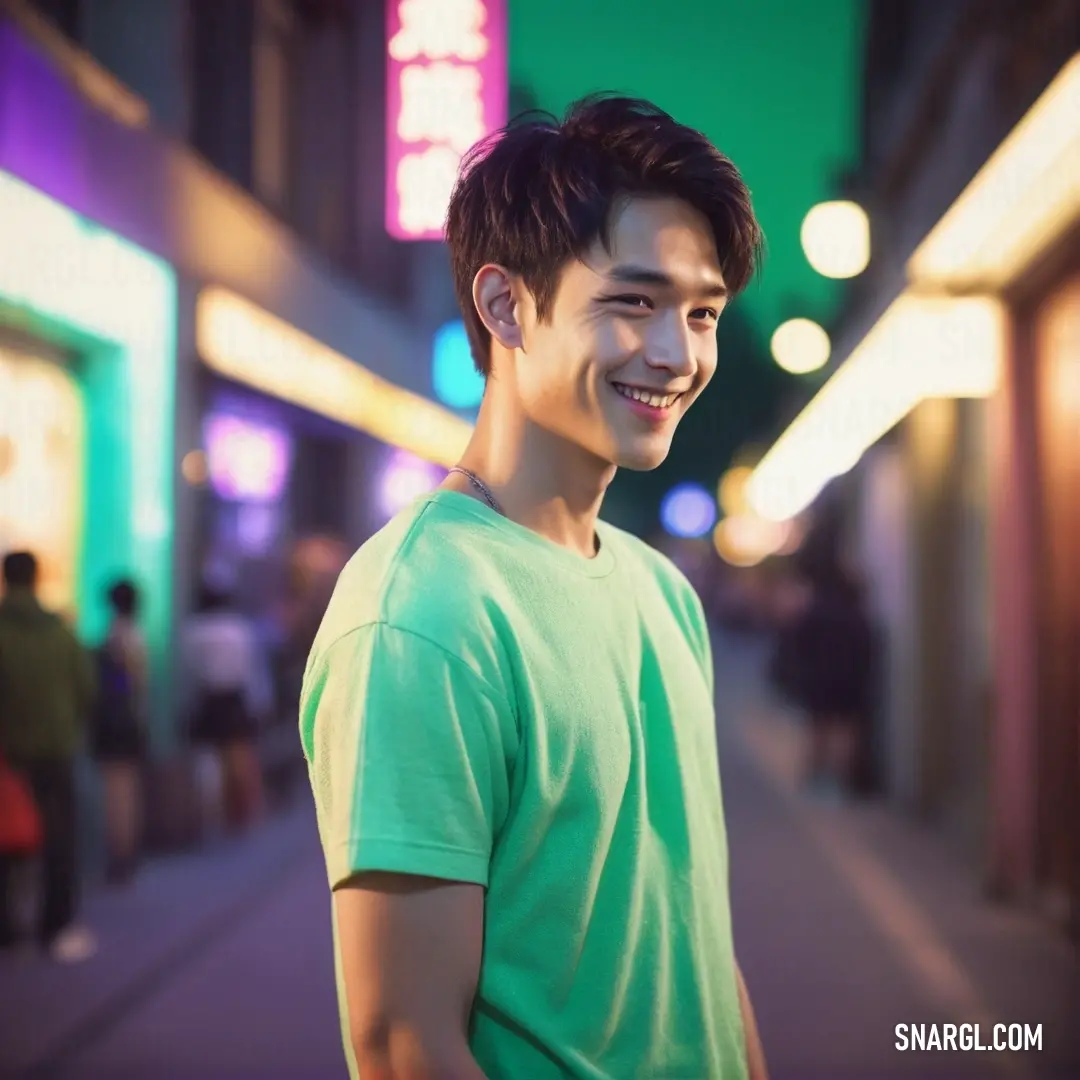 Granny Smith Apple color example: Man standing on a sidewalk in front of a building with neon lights on it's sides and a green shirt on