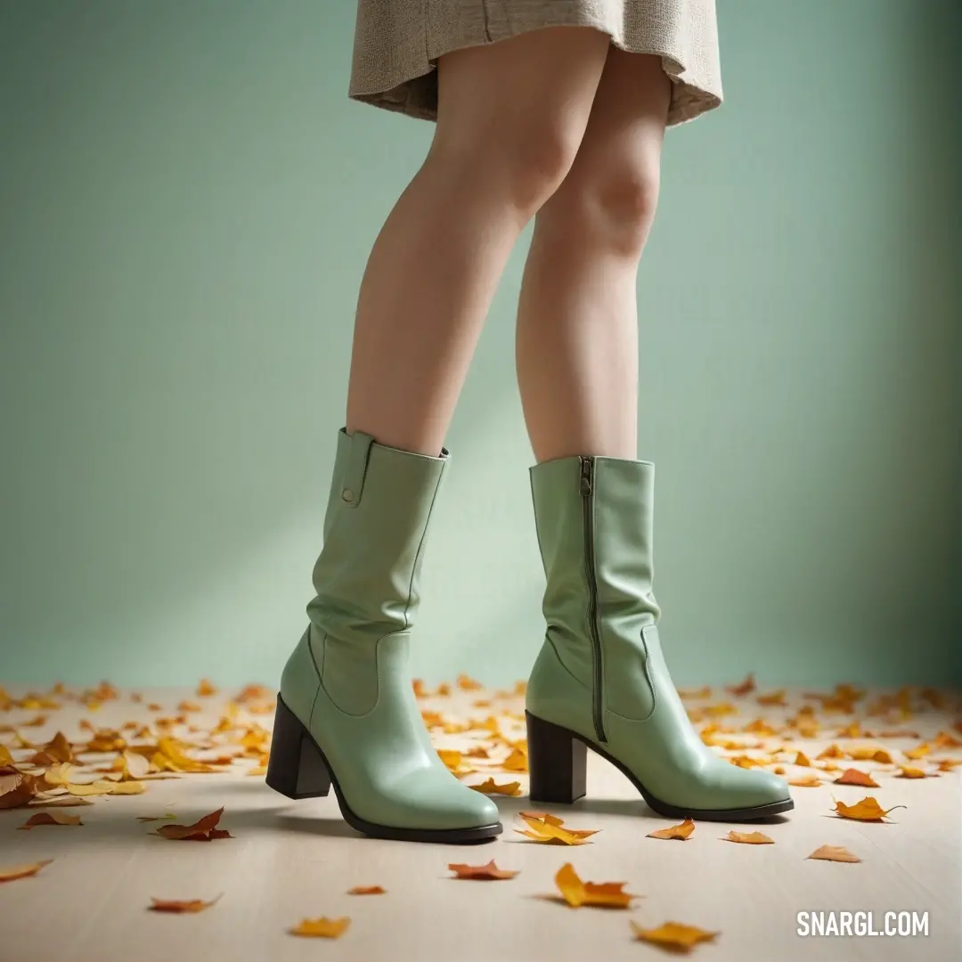 Woman's legs and boots are shown in front of leaves on the ground. Color Granny Smith Apple.