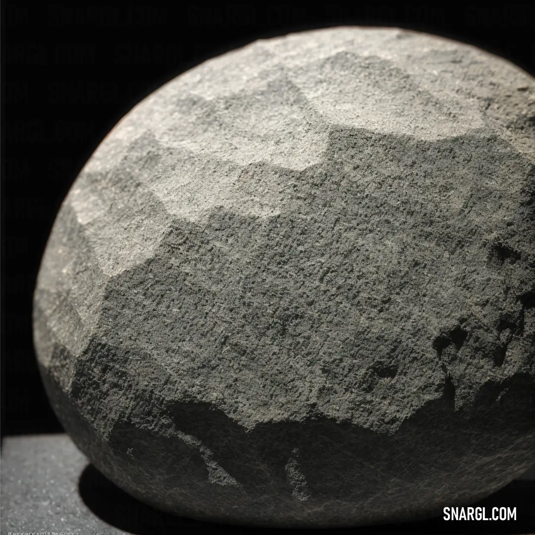 Large rock on top of a table next to a black wall and a black background with a shadow
