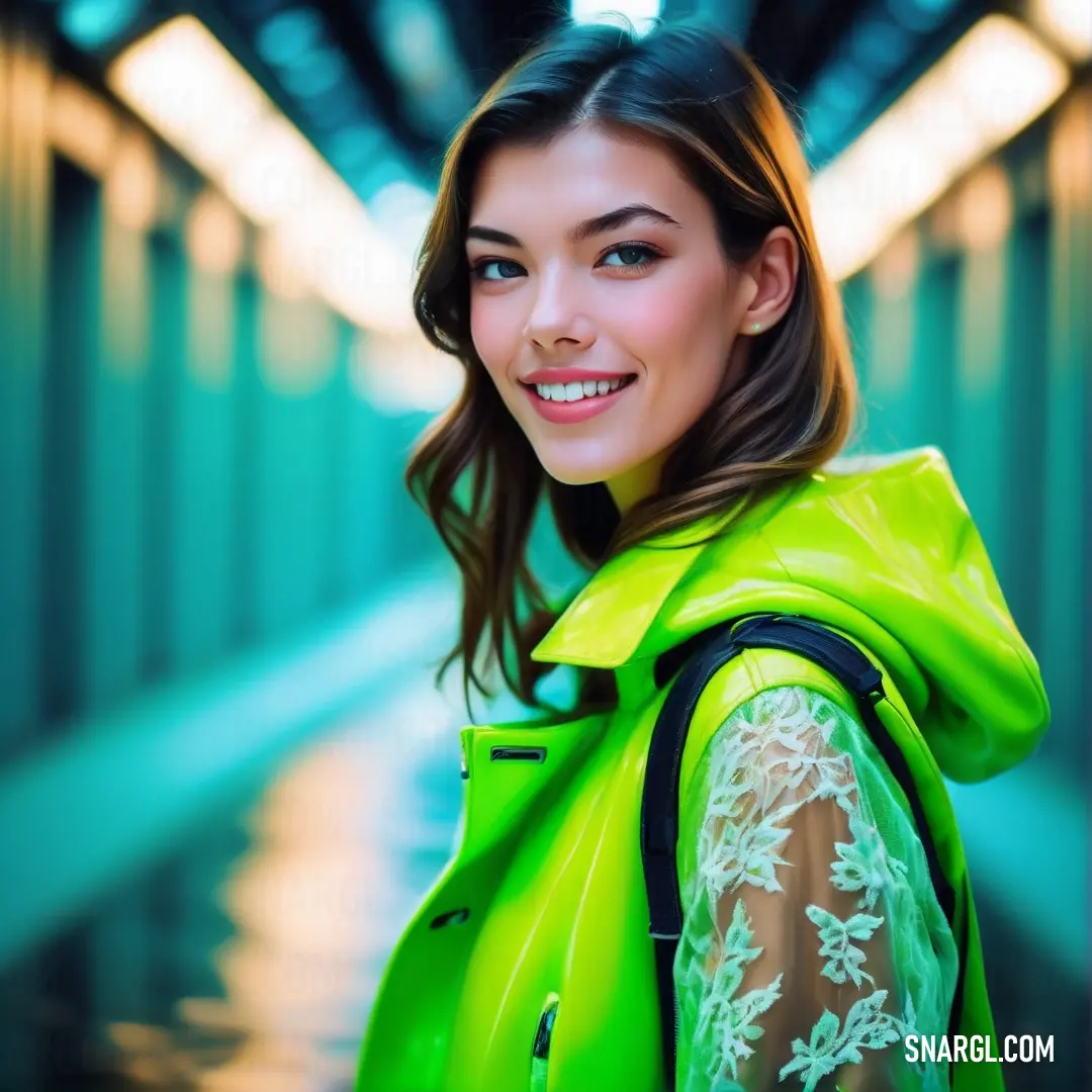 Woman in a green jacket is smiling for the camera while standing in a hallway. Example of #00FF00 color.