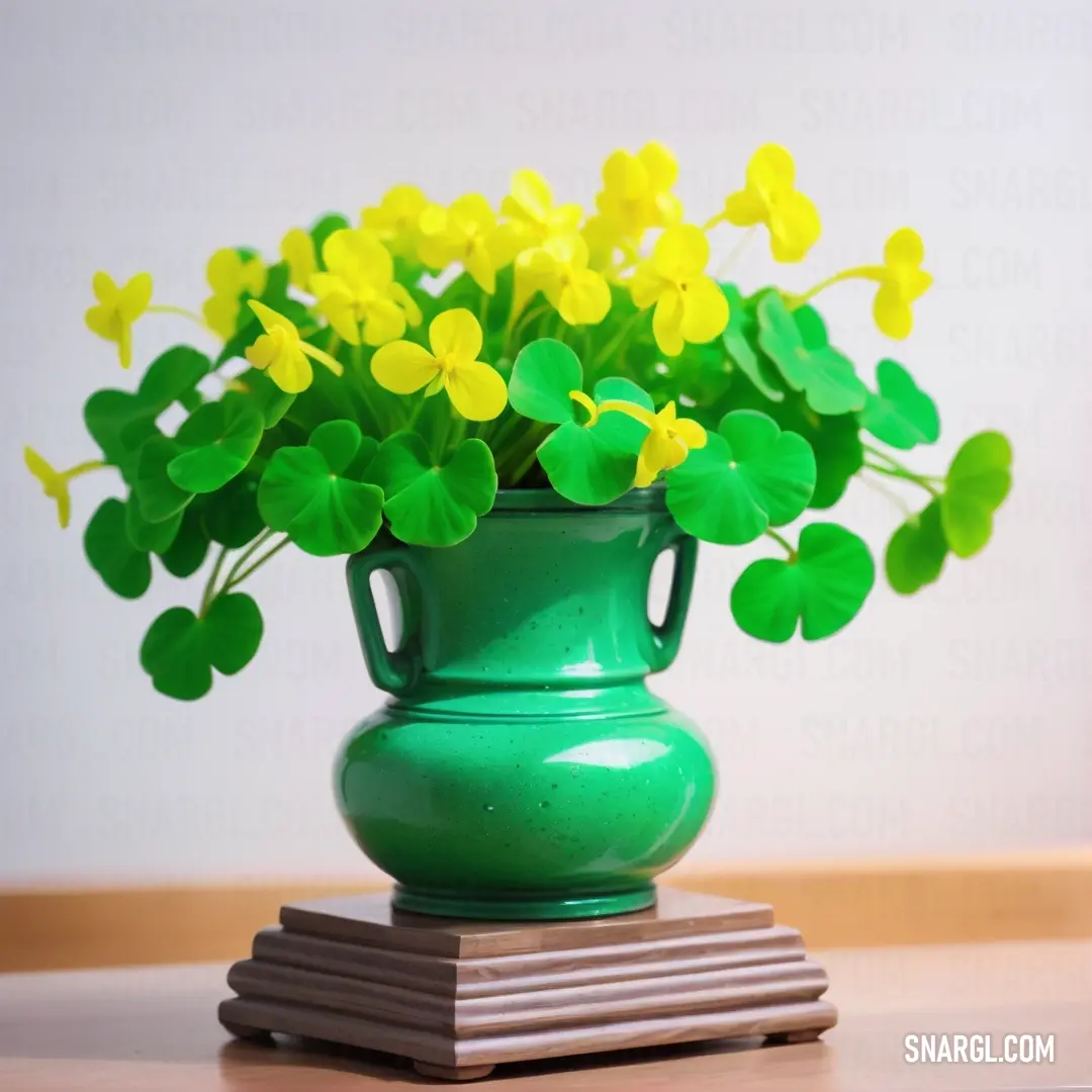 Green vase with yellow flowers in it on a table top with a stack of books and a white wall behind it. Color #00FF7F.