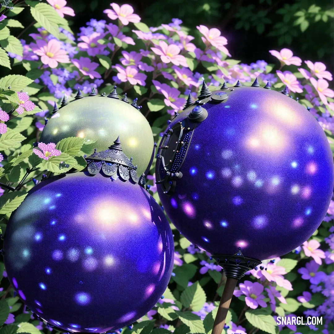 Two purple and green ornaments are on a tree branch with purple flowers in the background and a purple bush