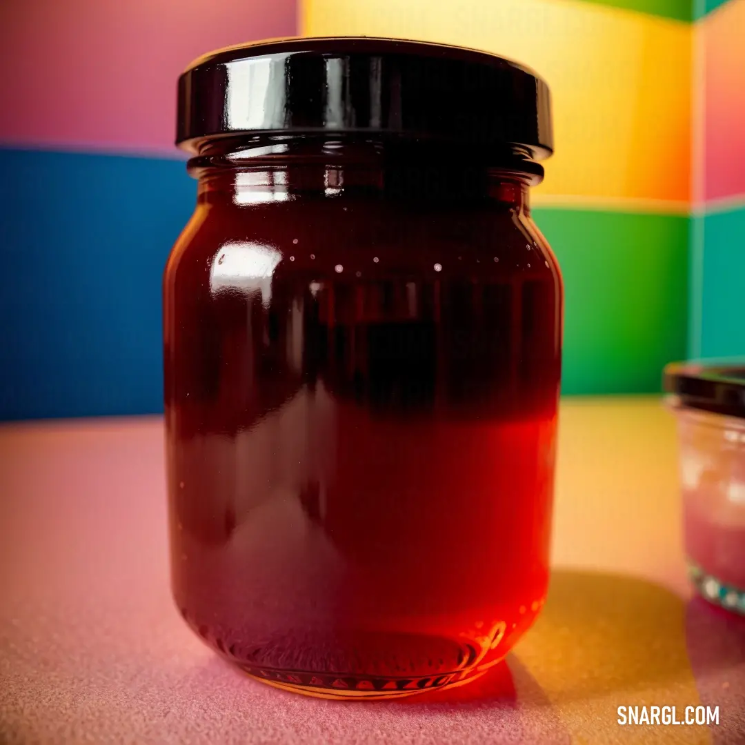 Jar of liquid on a table next to a container of liquid on a tablecloth with a colorful background