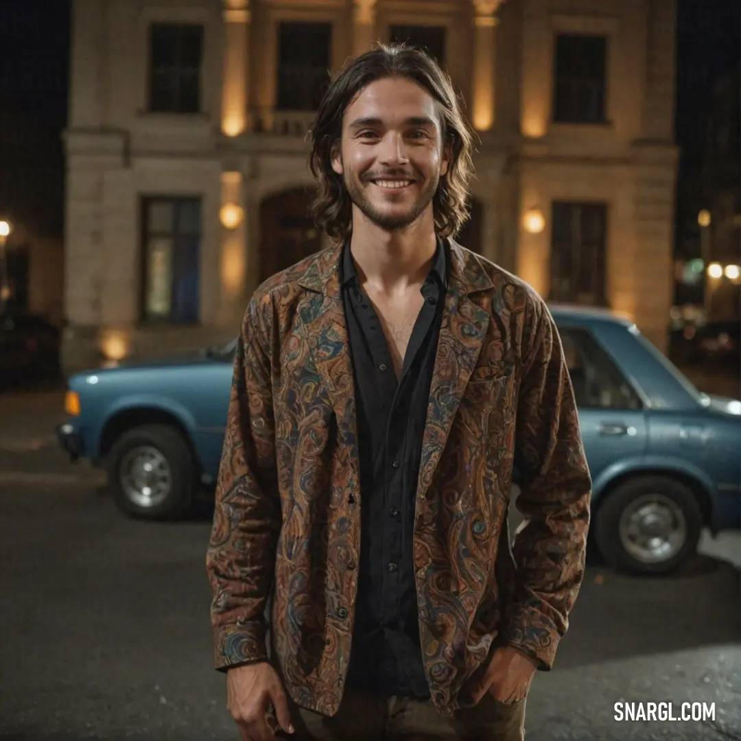 Man standing in front of a blue car in a parking lot at night with a building in the background