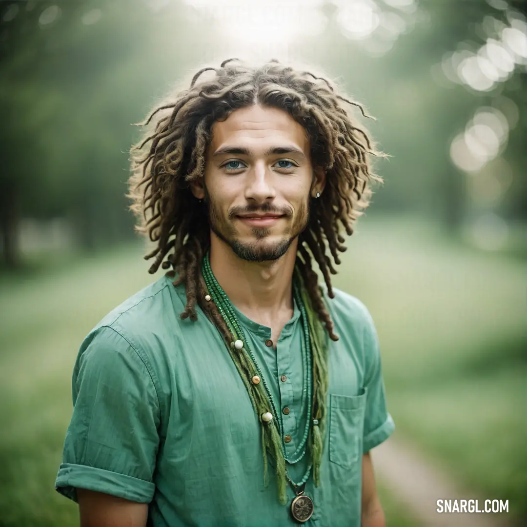 Man with dreadlocks standing in a park with a green shirt on