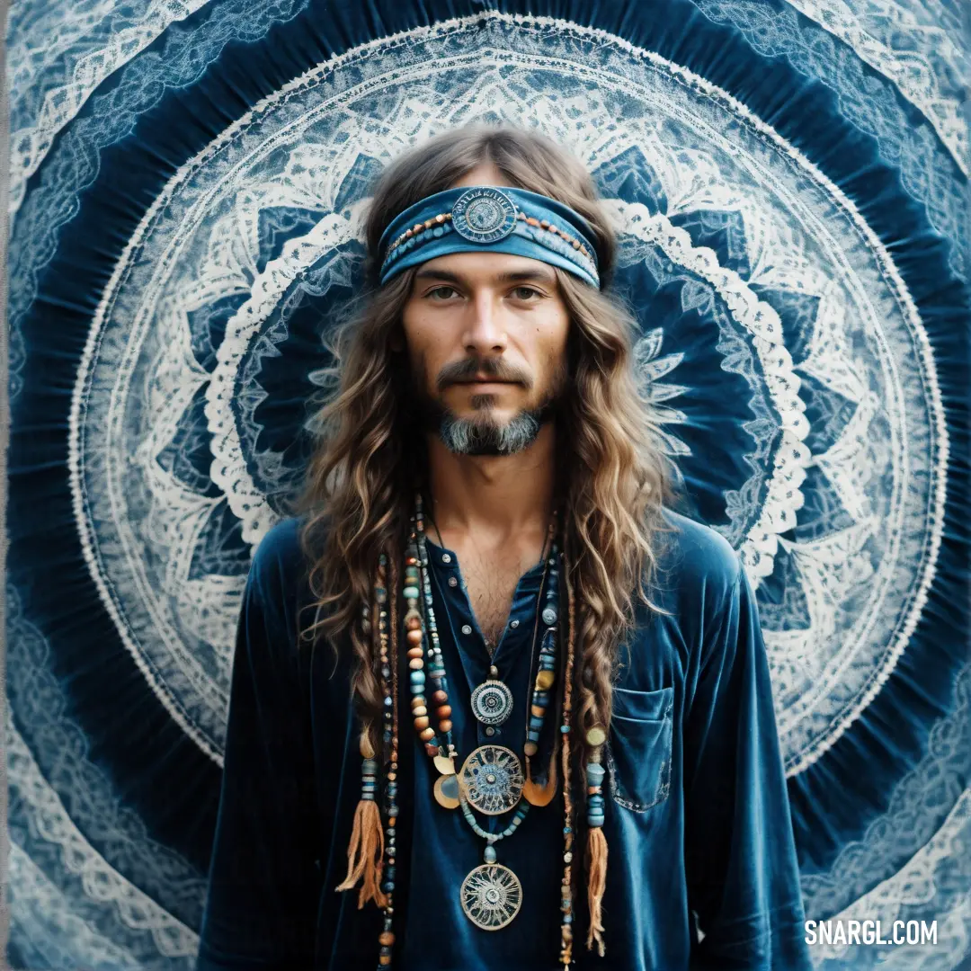 Man with long hair and a bandana on his head standing in front of a blue and white wall