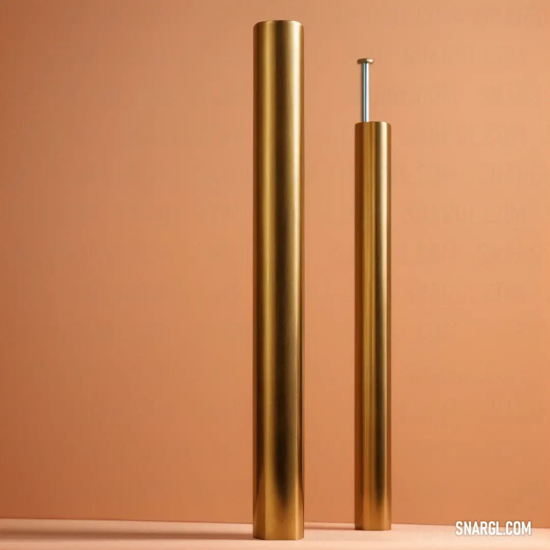 Indian yellow color example: Pair of gold colored metal poles on a table with a pink background