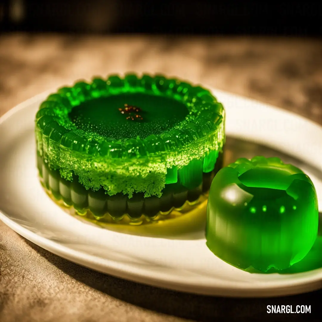 Green cake on top of a white plate next to a green pepper slicer on a plate