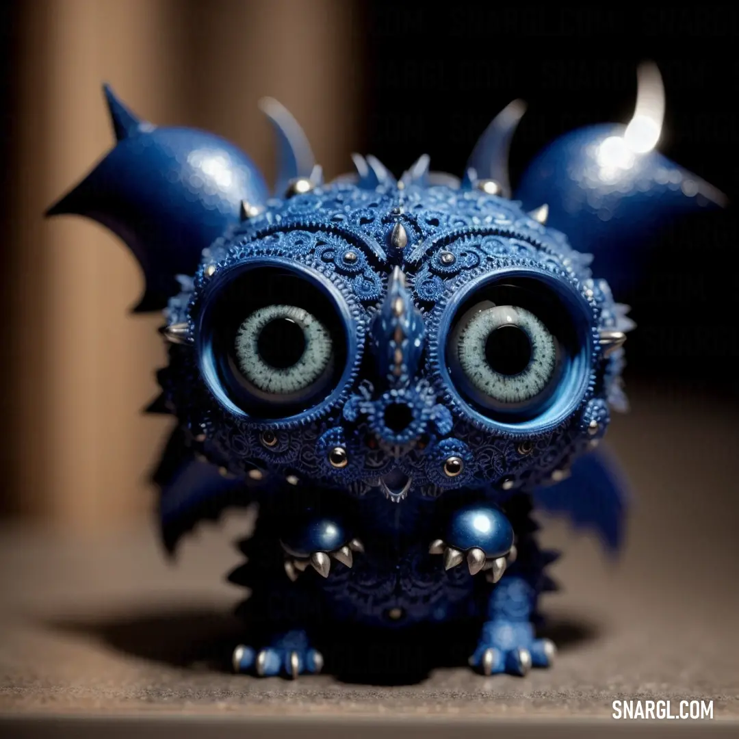 Blue toy with big eyes and spikes on it's head on a table with a dark background