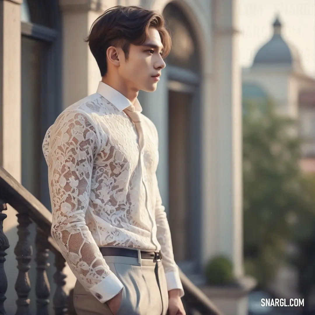 Man in a white shirt and tie standing on a balcony with a railing and a building in the background