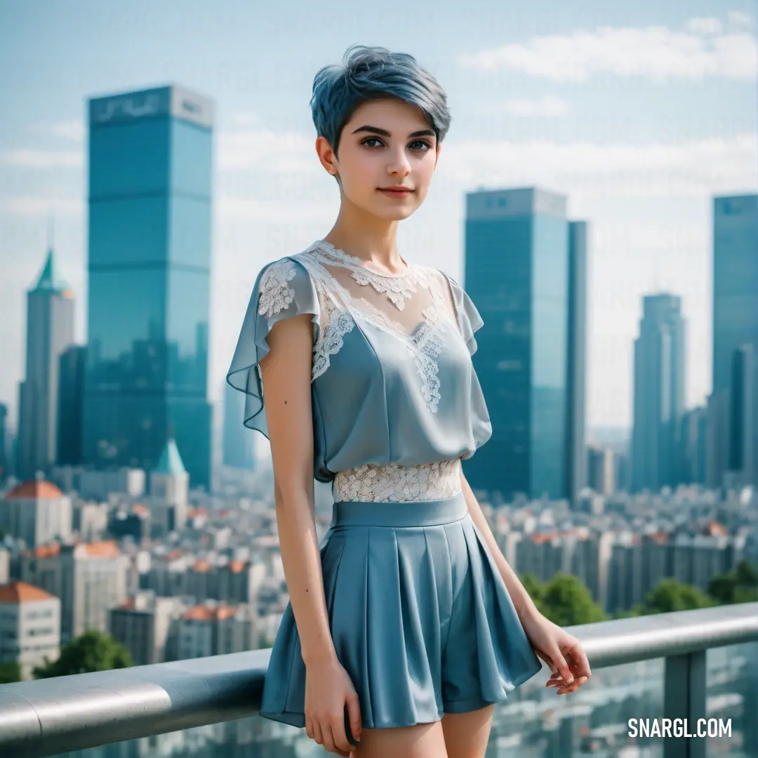 Woman standing on a balcony in front of a city skyline with tall buildings and a blue sky background