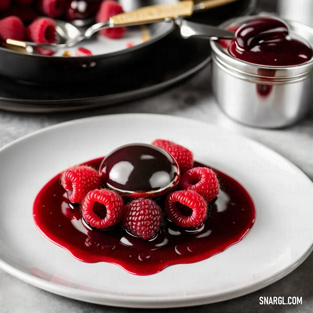 Plate of raspberries and chocolate sauce on a table with other plates of food in the background