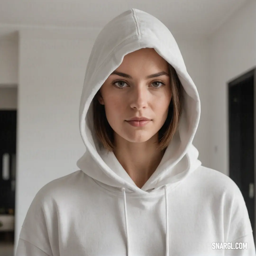 In a striking white hoodie, a woman gazes intently at the camera, her serious demeanor and soft features reflecting a balance of strength and vulnerability. The muted background adds depth to her thoughtful expression.