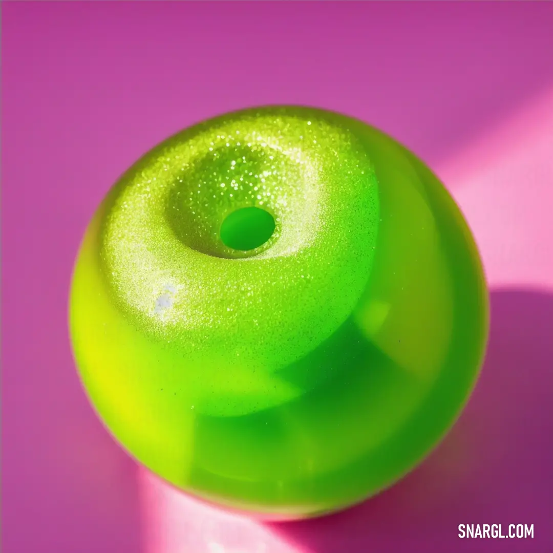 Green ball on top of a pink surface with a green center piece in the middle of the ball