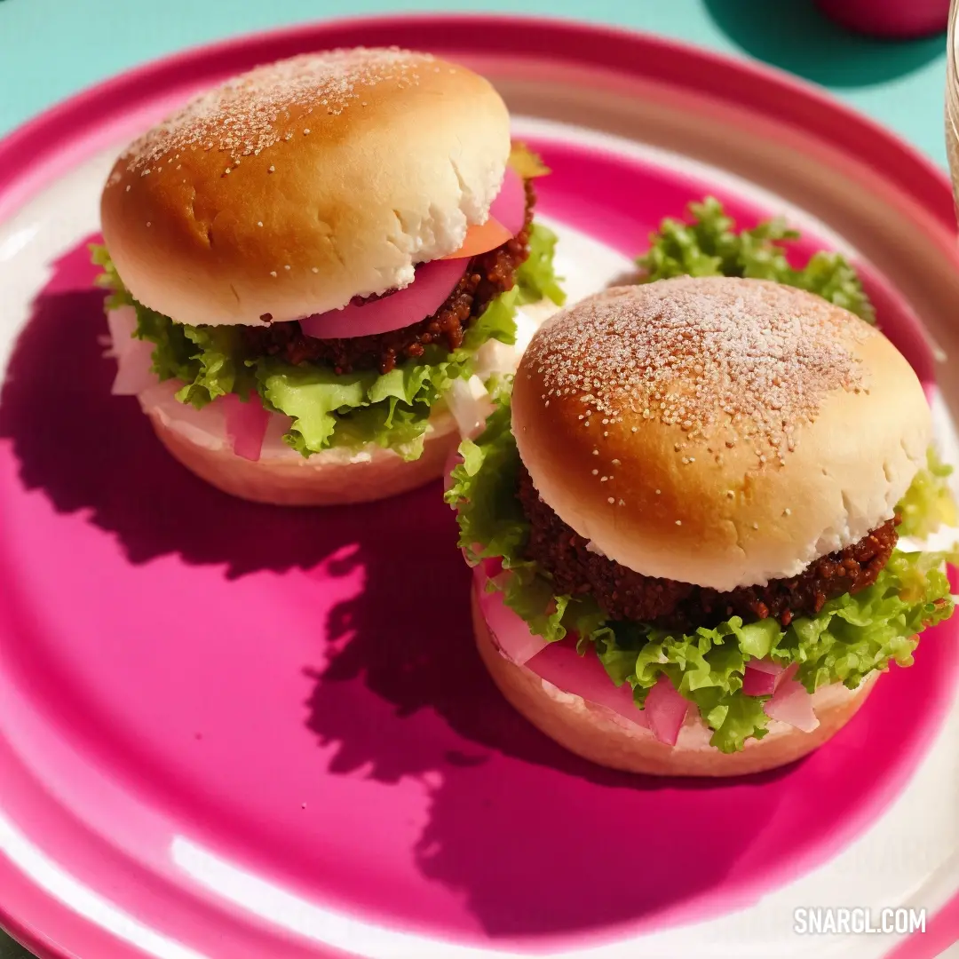 Two hamburgers on a pink plate with a drink on the side of the plate